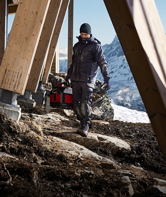 Person walking with a cart on a construction site with mountains in the background