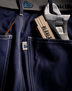 Navy blue work pants with tools and a Blaklader branded belt in the pocket