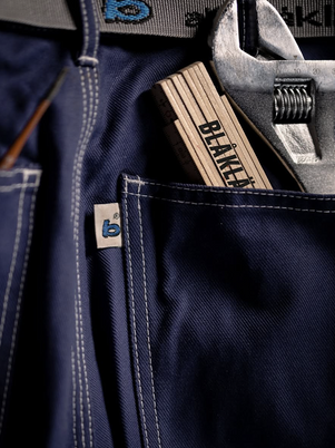 Navy blue work pants with a wrench and pliers in the pocket, featuring 'BLÅKLÄDER' branding.