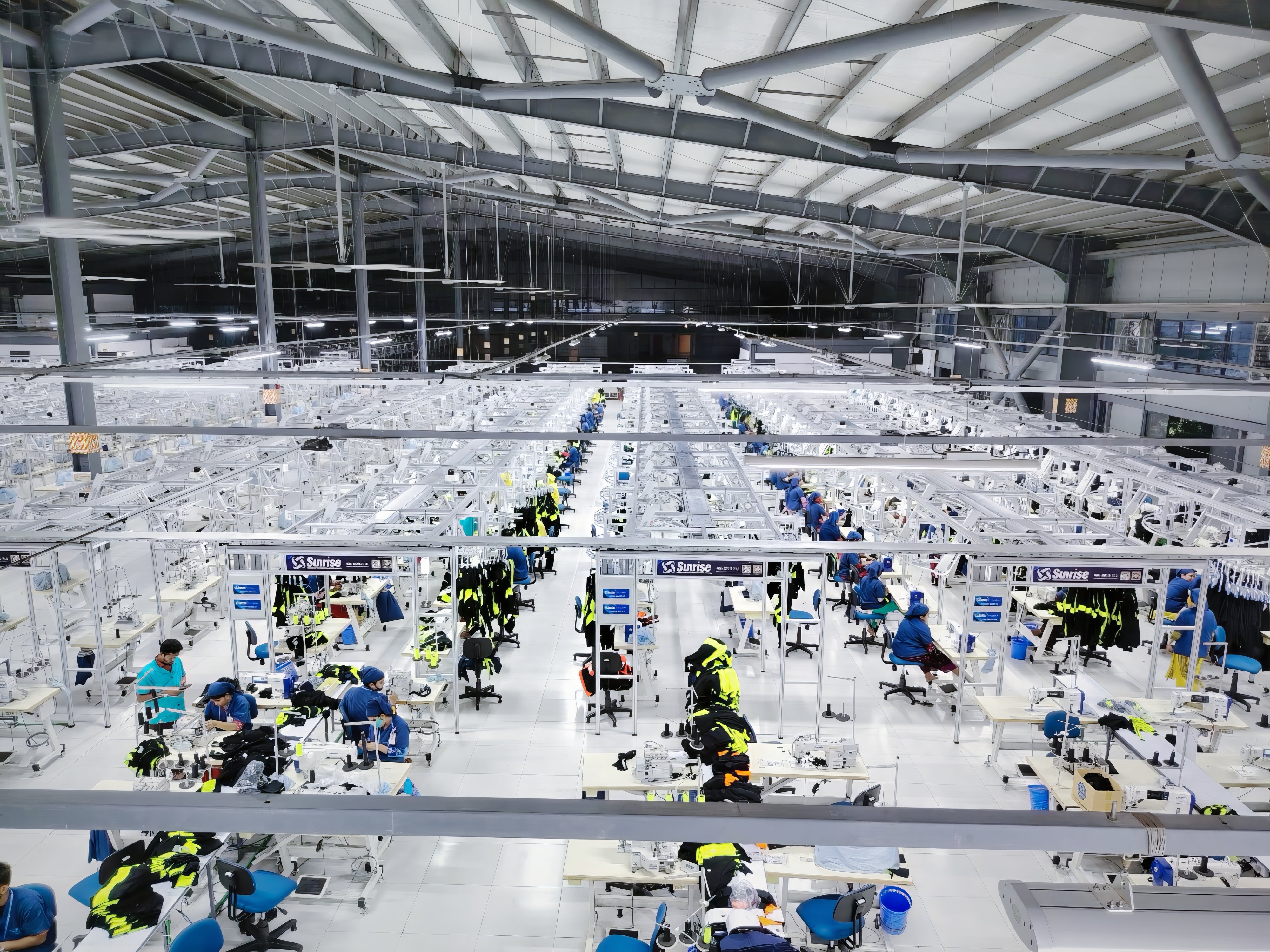 Large industrial factory with multiple workers on assembly lines.