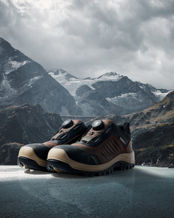 Pair of hiking boots on a frozen lake with mountains in the background